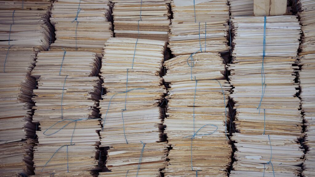 Bundles of paper records tied with blue string and stacked in rows, the kind of job records a service business sends back to Google Ads