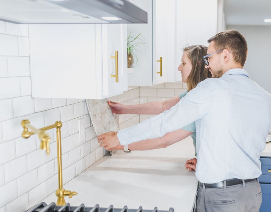 Couple holding a mosaic tile sample against a kitchen backsplash, the kind of planned, visual project a contractor can sell with Facebook ads
