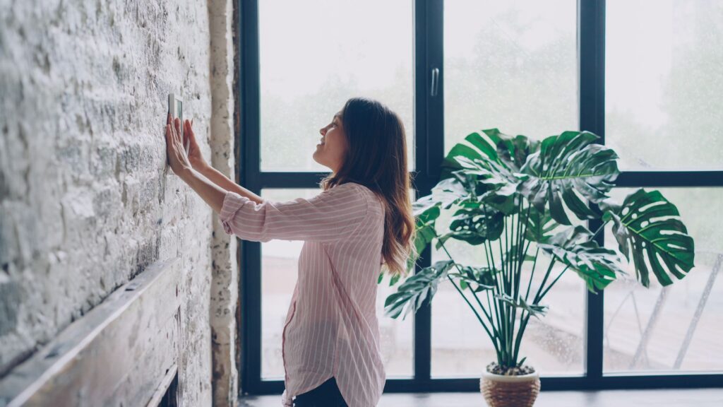 Homeowner adjusting a wall thermostat at home, the kind of customer an HVAC company reaches through Local Services Ads or Search ads